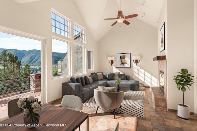 tiled living room featuring a mountain view, ceiling fan, a fireplace, and a wealth of natural light