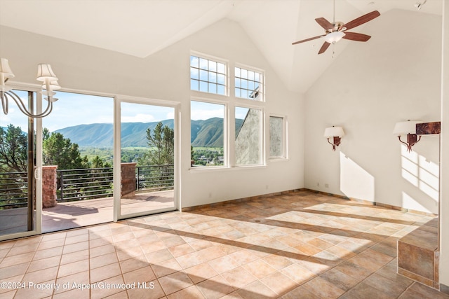 unfurnished living room with a mountain view, light tile patterned floors, ceiling fan with notable chandelier, and high vaulted ceiling