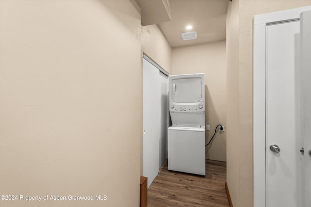 washroom featuring dark hardwood / wood-style flooring and stacked washing maching and dryer