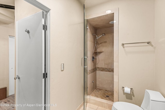 bathroom featuring toilet and a shower with shower door