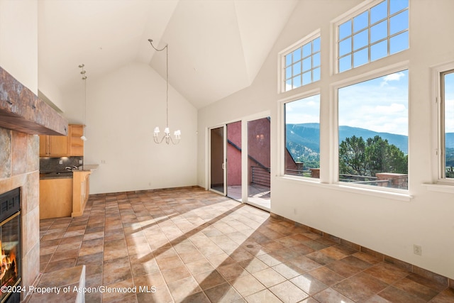 unfurnished living room featuring an inviting chandelier, wine cooler, a mountain view, a towering ceiling, and a tiled fireplace