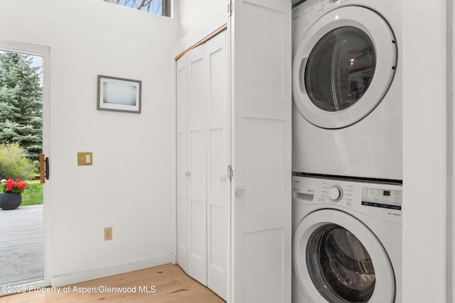 laundry room featuring light wood-type flooring, stacked washer and clothes dryer, and laundry area