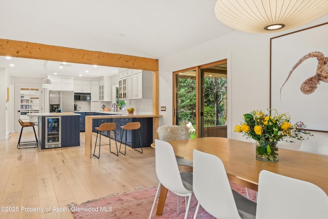 dining area with wine cooler, recessed lighting, light wood-style flooring, and vaulted ceiling