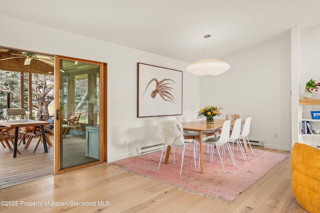dining room featuring a ceiling fan, a baseboard heating unit, and light wood-style flooring