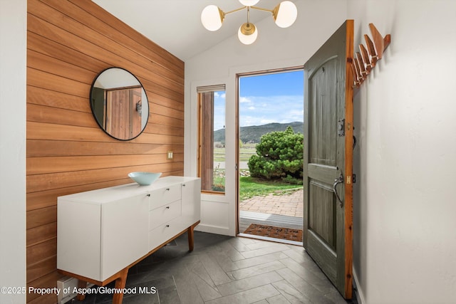 entrance foyer with wooden walls, a mountain view, a chandelier, and lofted ceiling