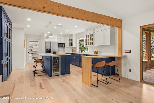 kitchen featuring a breakfast bar area, white cabinetry, appliances with stainless steel finishes, blue cabinets, and wine cooler