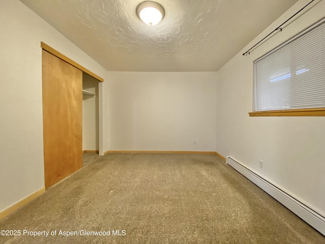 interior space featuring carpet, a textured ceiling, a baseboard radiator, and a closet