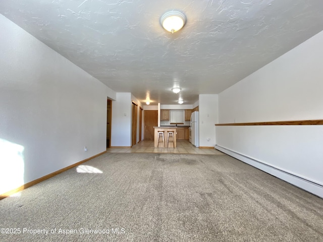 unfurnished living room featuring a textured ceiling, baseboard heating, and light carpet