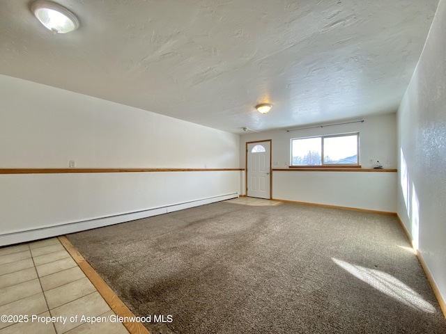 tiled empty room featuring baseboard heating