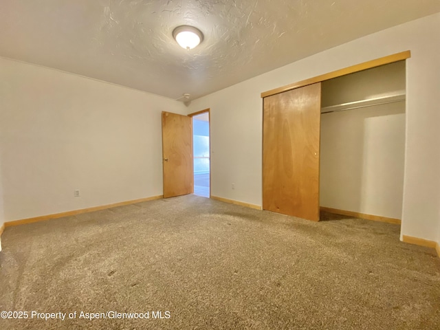 unfurnished bedroom featuring a textured ceiling, carpet floors, and a closet