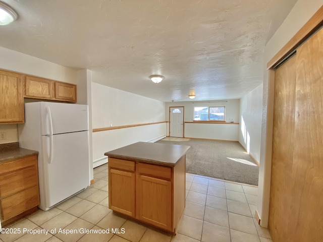 kitchen featuring white fridge, a kitchen island, baseboard heating, and light colored carpet