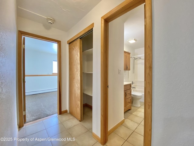 corridor with light tile patterned floors and baseboard heating