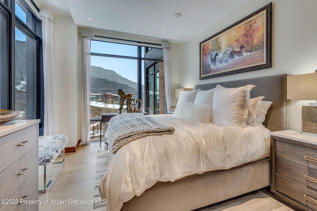 bedroom with a mountain view and light hardwood / wood-style flooring