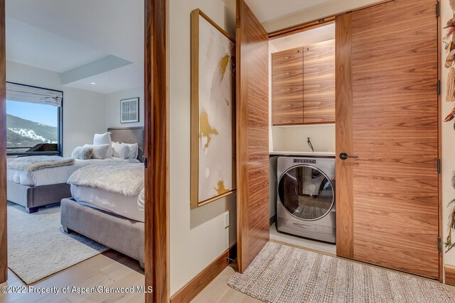 laundry room with cabinets, light hardwood / wood-style floors, and washer / dryer