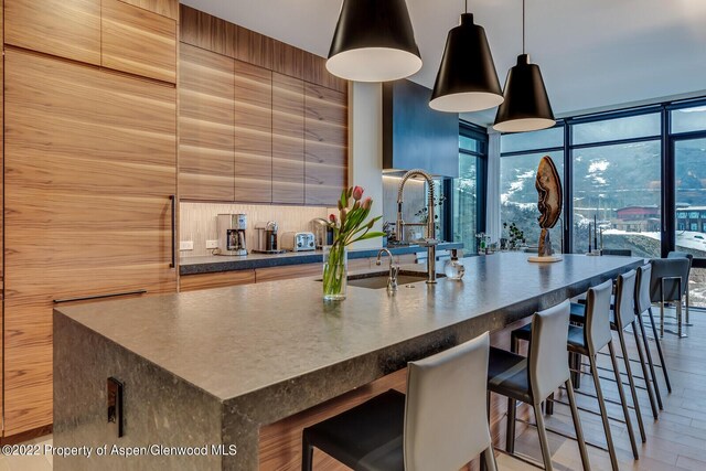 kitchen featuring floor to ceiling windows, wood walls, sink, and pendant lighting