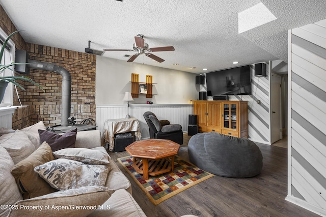 1617 W 7th St, Rifle, CO 81650 - living area with a wood stove, a ceiling fan, wood finished floors, a textured ceiling, and a wainscoted wall