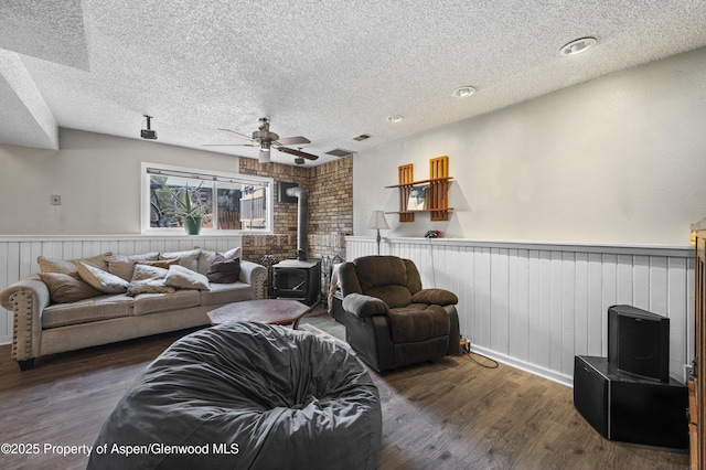 1617 W 7th St, Rifle, CO 81650 - living room featuring a wood stove, a textured ceiling, wainscoting, ceiling fan, and wood finished floors