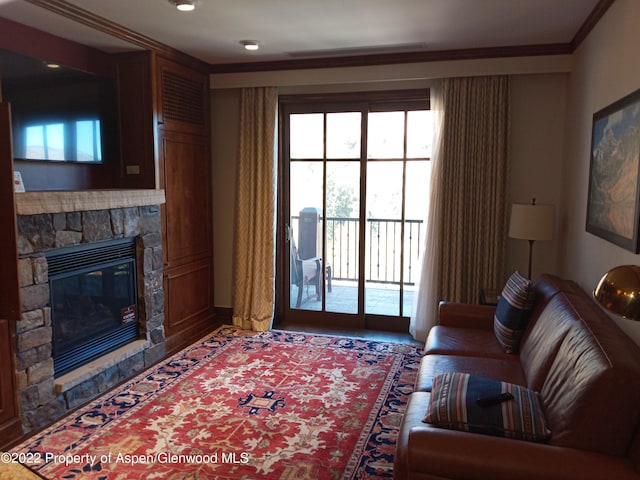 living room with a stone fireplace and ornamental molding