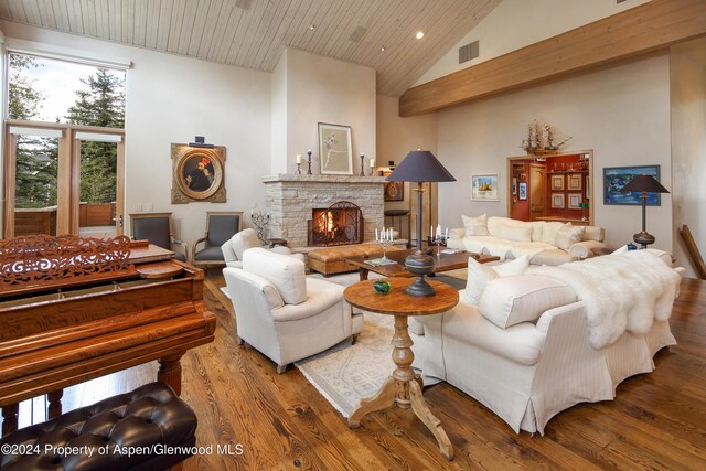 living room with high vaulted ceiling, a stone fireplace, and hardwood / wood-style floors