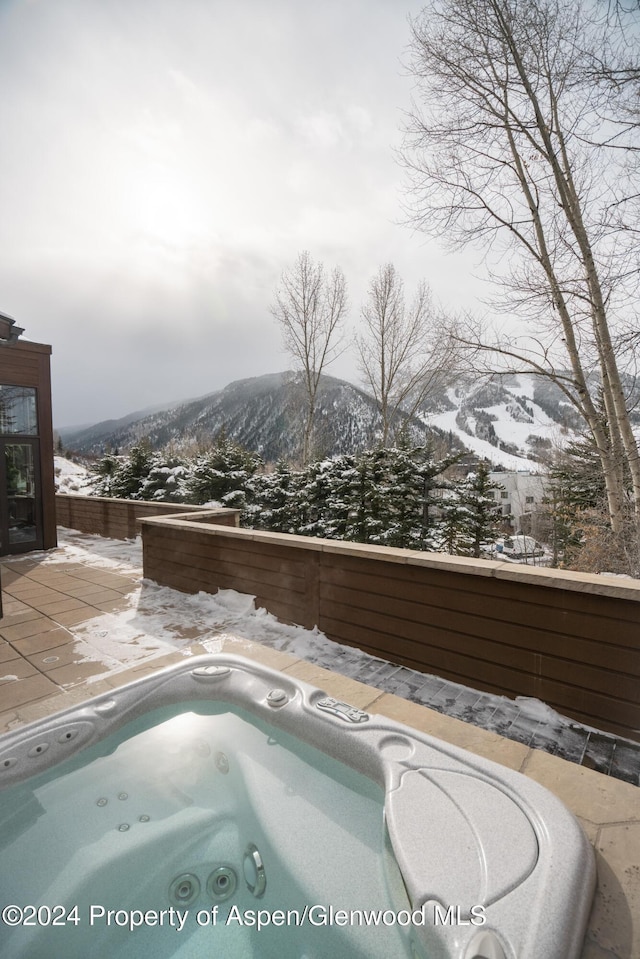 snow covered pool featuring an outdoor hot tub and a mountain view