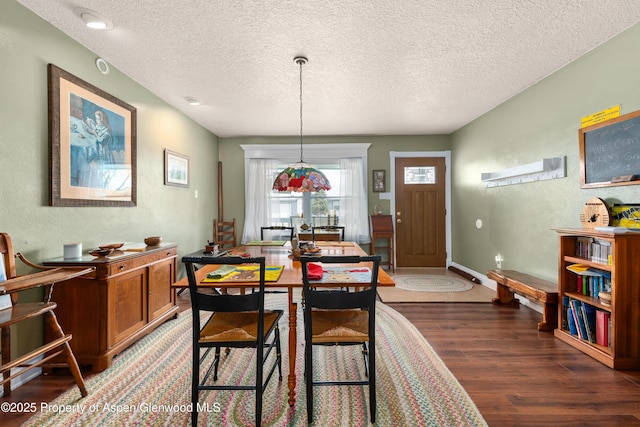 dining area featuring wood finished floors, a textured ceiling, a textured wall, and baseboards