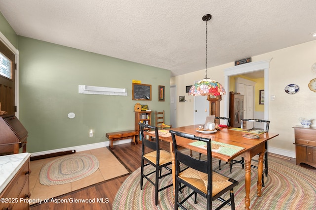 dining space featuring wood finished floors, a textured ceiling, and baseboards
