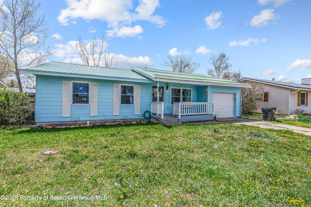 ranch-style house with a porch, an attached garage, concrete driveway, metal roof, and a front lawn