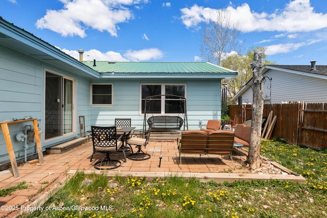 rear view of property with a patio area, fence, metal roof, and outdoor lounge area