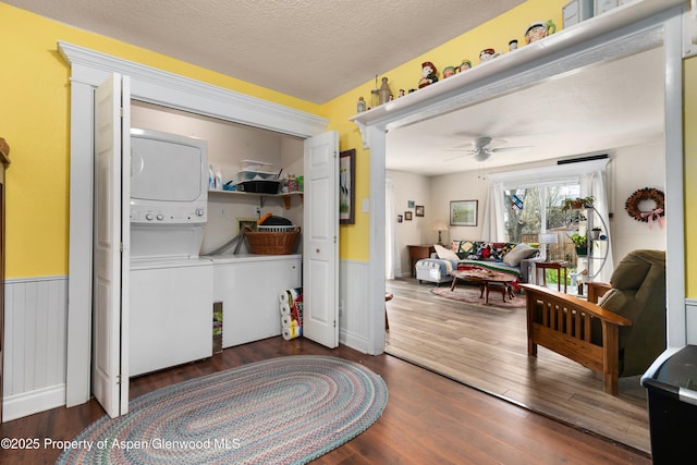 foyer with stacked washing machine and dryer, wainscoting, wood finished floors, and ceiling fan