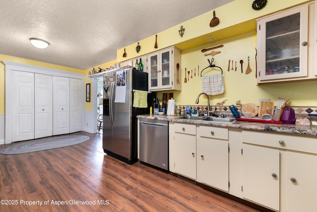 kitchen featuring a sink, stainless steel appliances, a textured ceiling, dark wood-style floors, and white cabinetry