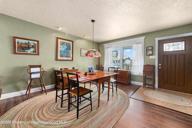 dining space with wood finished floors, baseboards, and a textured ceiling