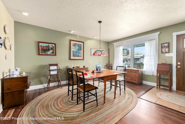 dining area featuring wood finished floors, a textured ceiling, and baseboards