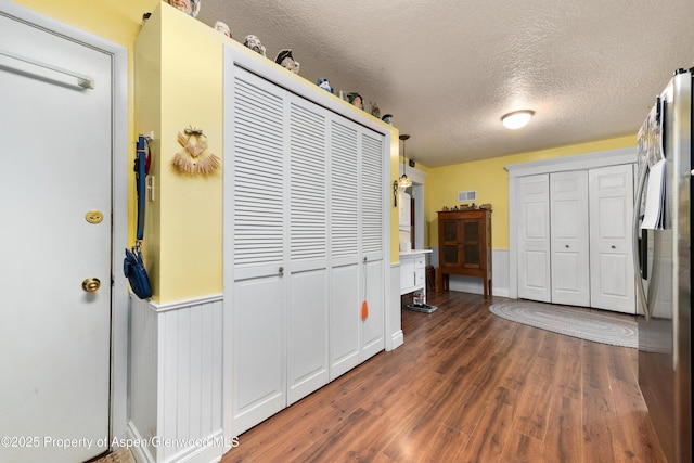 bedroom with freestanding refrigerator, wood finished floors, and a textured ceiling