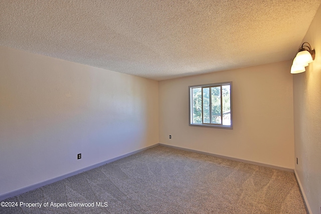 carpeted spare room with a textured ceiling