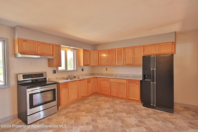 kitchen with sink, light brown cabinets, black fridge, and stainless steel range with electric cooktop