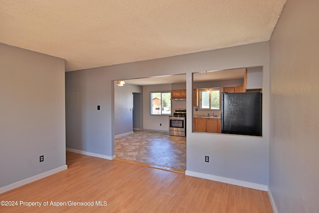 unfurnished living room with a textured ceiling, light hardwood / wood-style floors, and sink