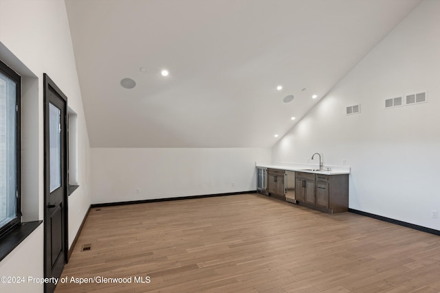 bonus room featuring light wood-type flooring, lofted ceiling, and sink