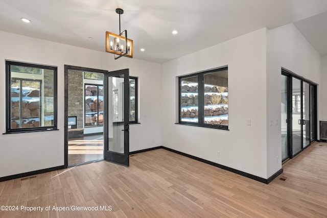 spare room featuring french doors, a notable chandelier, and light wood-type flooring