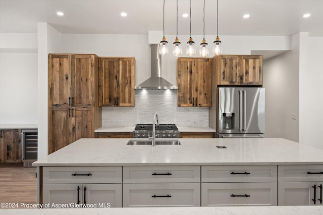 kitchen featuring sink, wall chimney exhaust hood, stainless steel fridge with ice dispenser, light stone counters, and pendant lighting