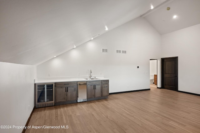 bar with light wood-type flooring, dark brown cabinetry, sink, high vaulted ceiling, and wine cooler