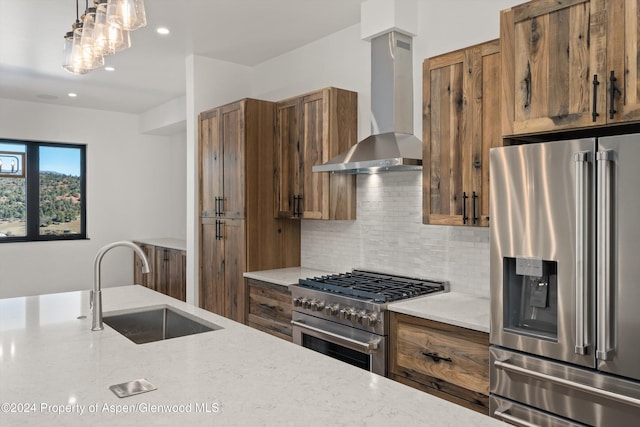 kitchen with wall chimney range hood, sink, hanging light fixtures, appliances with stainless steel finishes, and tasteful backsplash