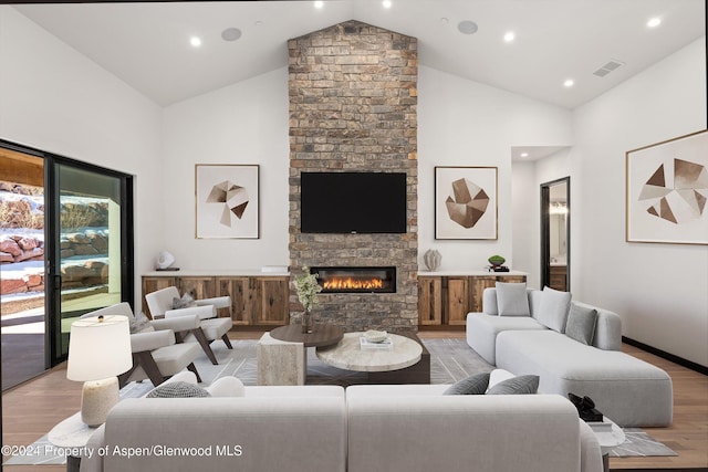 living room featuring a fireplace, high vaulted ceiling, and light wood-type flooring