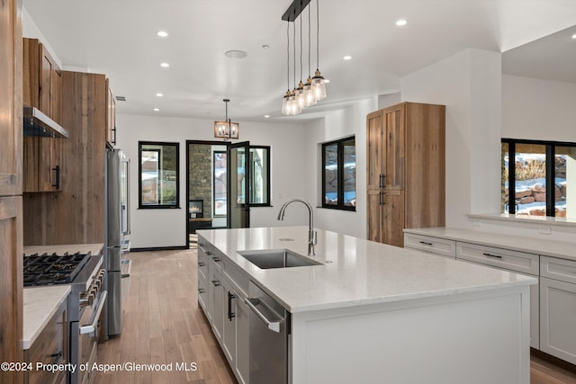 kitchen featuring a kitchen island with sink, sink, white cabinets, and appliances with stainless steel finishes