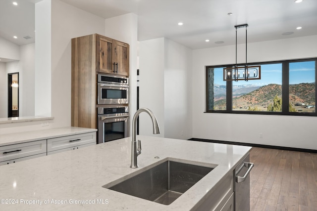 kitchen featuring light stone countertops, sink, pendant lighting, and an inviting chandelier