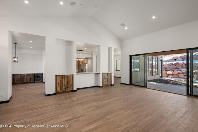 unfurnished living room with light hardwood / wood-style floors and high vaulted ceiling