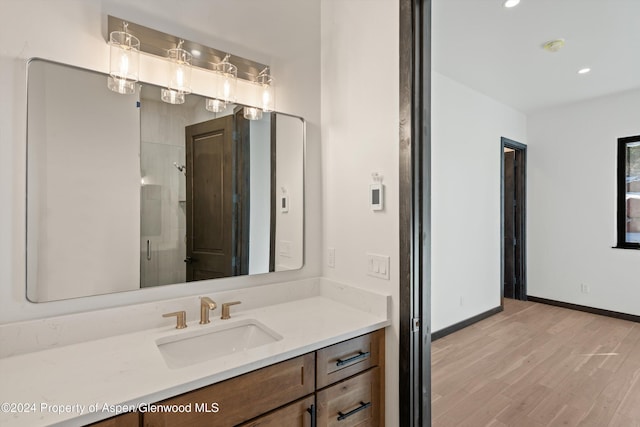 bathroom with hardwood / wood-style floors, vanity, and a shower with shower door