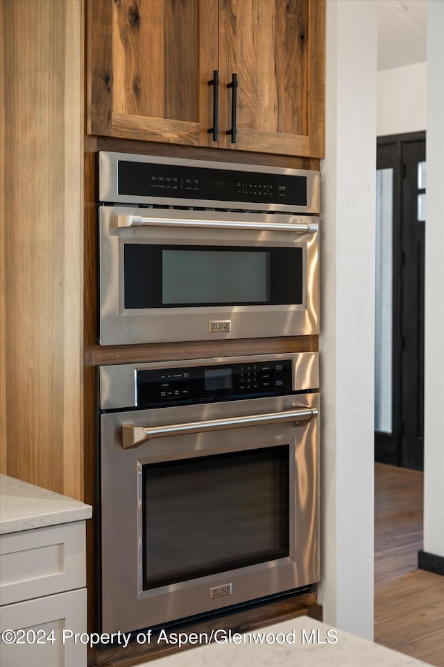 kitchen with white cabinetry, double oven, and light stone counters