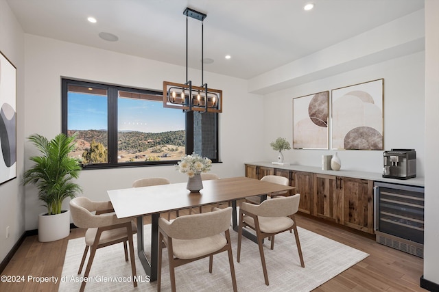 dining room featuring a chandelier, light hardwood / wood-style flooring, and beverage cooler