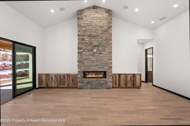 unfurnished living room featuring a fireplace, high vaulted ceiling, and light wood-type flooring