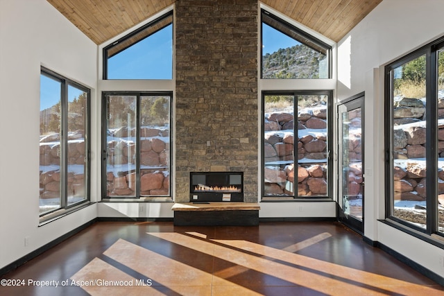 interior space featuring lofted ceiling, a stone fireplace, and wooden ceiling